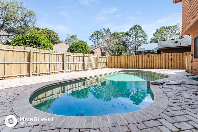 a backyard pool with a wooden fence and a house