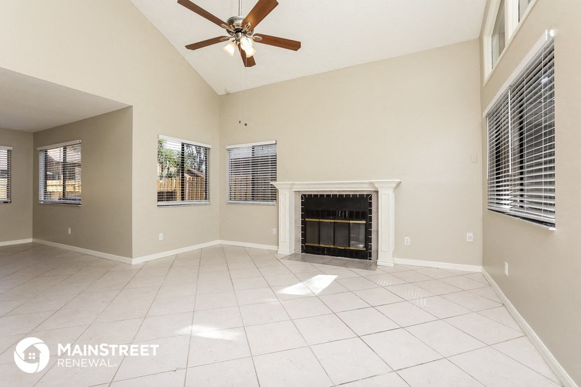 an empty living room with a fireplace and a ceiling fan