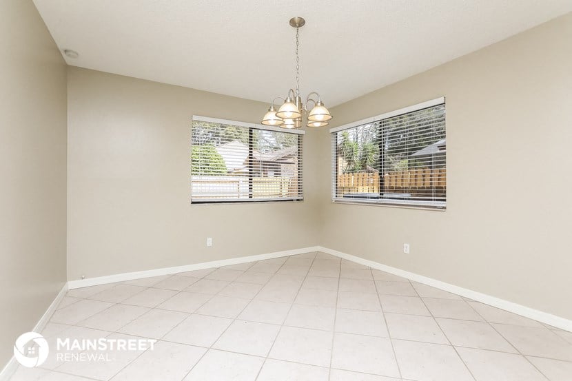 an empty dining room with two windows and a tiled floor