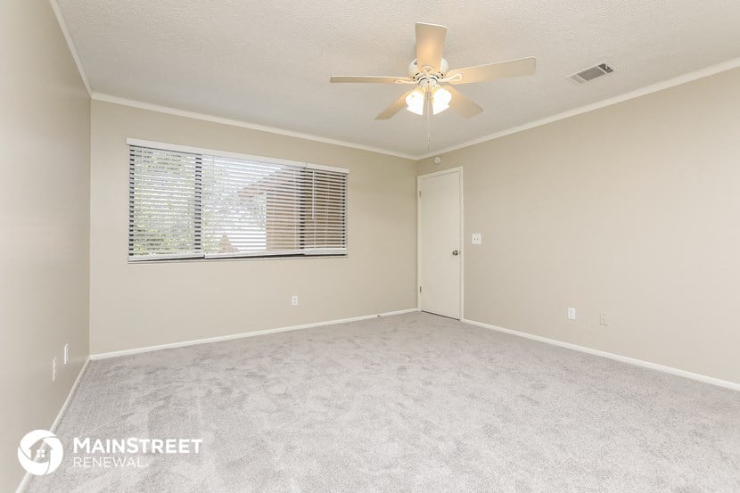 a spacious living room with a ceiling fan and a window