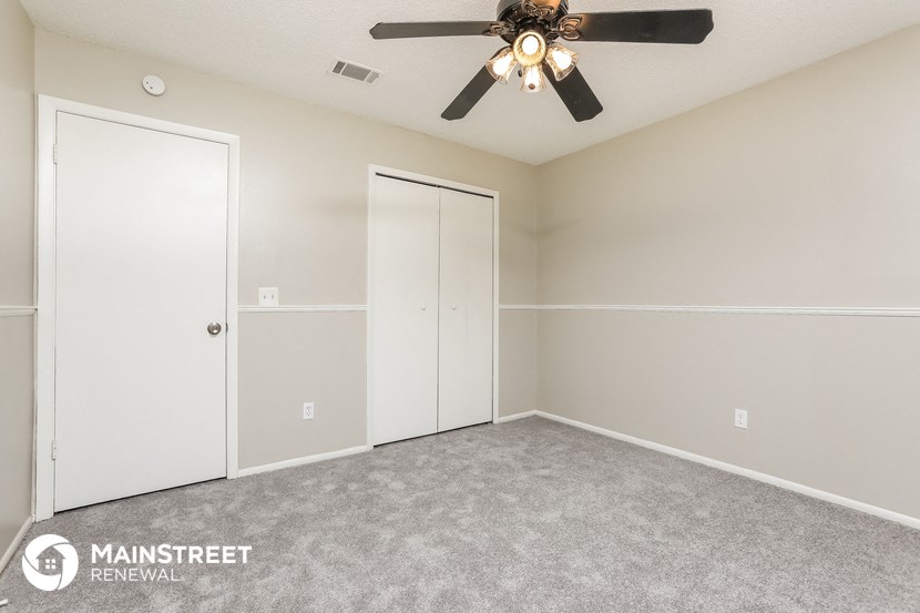 a bedroom with a ceiling fan and a closet