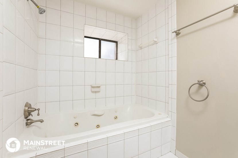 a white tiled bathroom with a tub and a shower