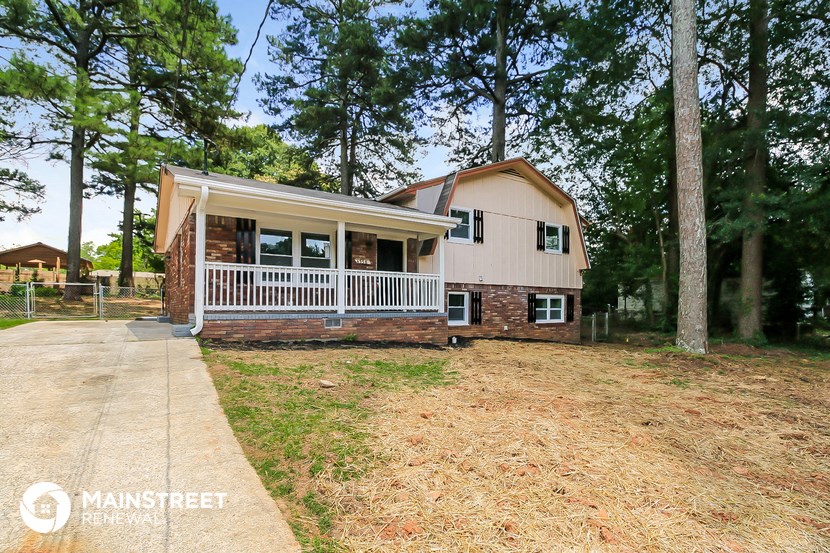 a white and brick house with a porch and some trees