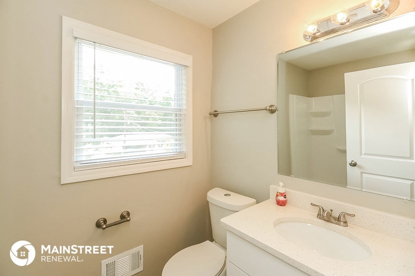 a bathroom with a toilet sink and mirror and a window