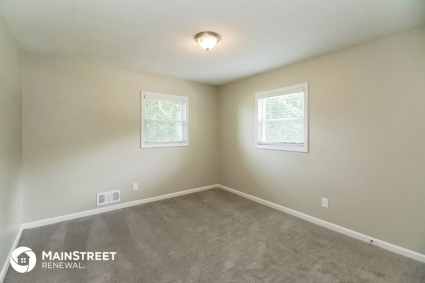 the spacious bedroom with carpeted flooring and two windows