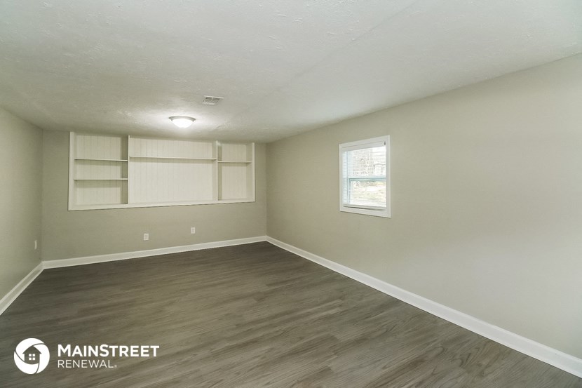 the interior of an empty room with wood flooring and a window