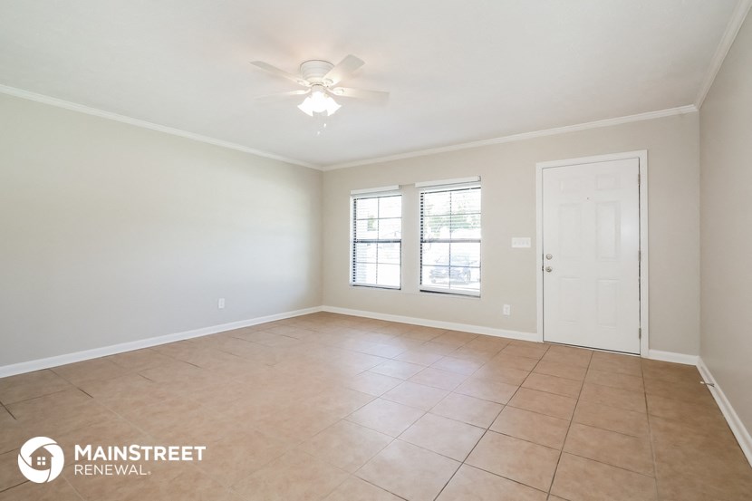 an empty living room with a ceiling fan