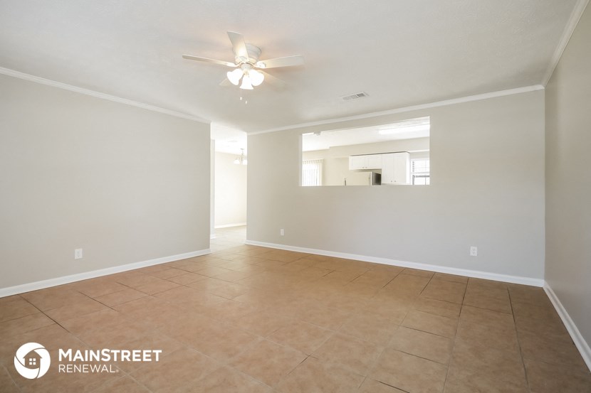 the spacious living room with tile flooring and a ceiling fan
