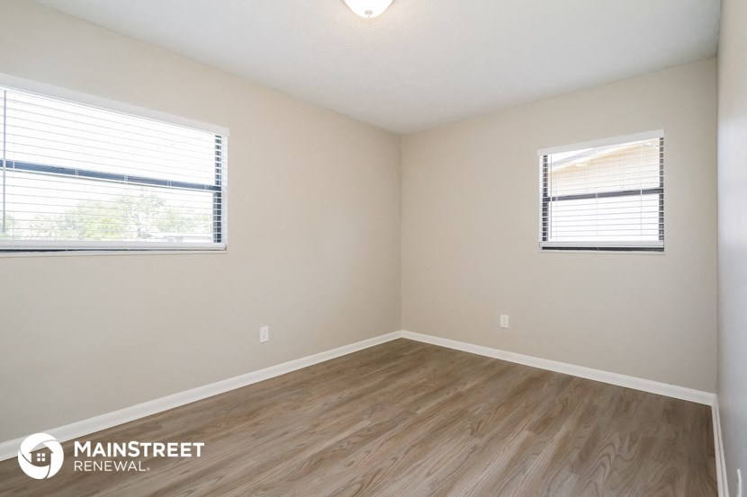 the spacious living room with wood flooring and two windows