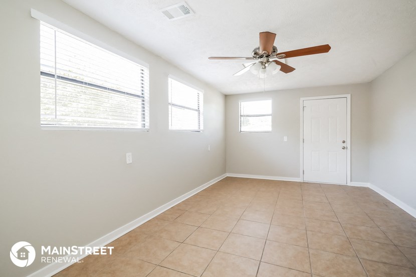 an empty living room with a ceiling fan and tiled floors