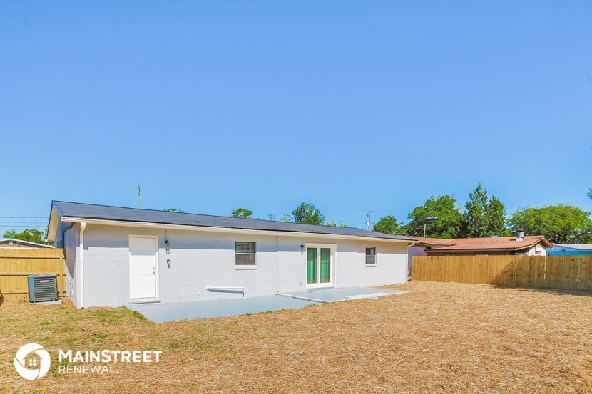 a small white house with green doors and a yard