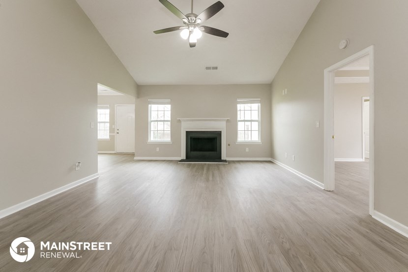 the spacious living room with fireplace and ceiling fan