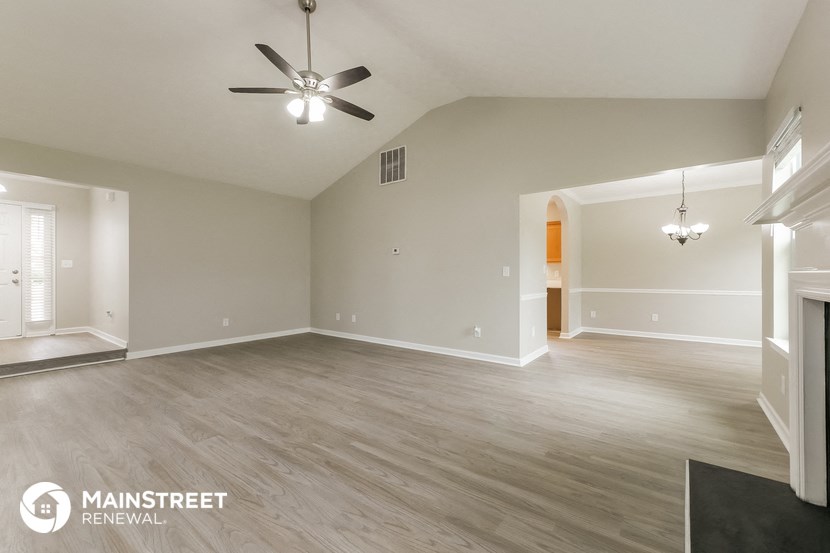 an empty living room with a ceiling fan and wood flooring
