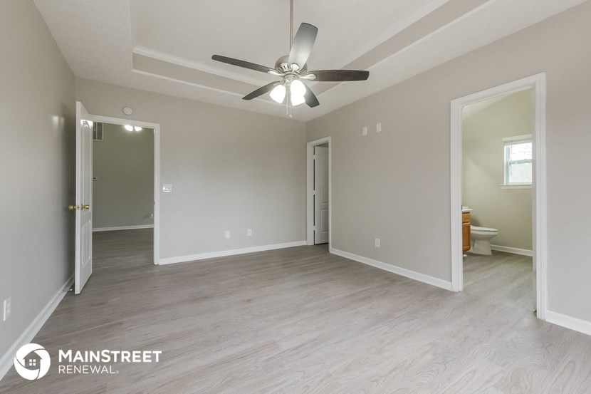 the spacious living room with ceiling fan and hardwood flooring