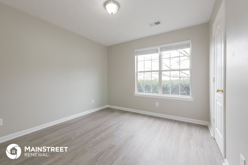 the spacious living room with wood flooring and a large window