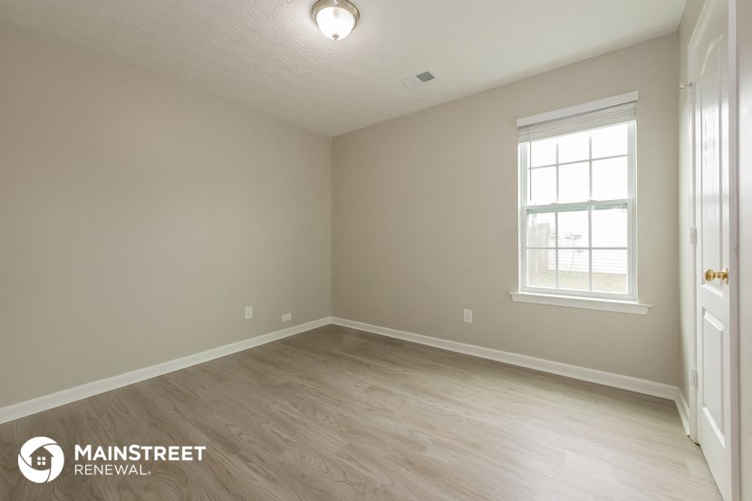 the interior of an empty room with wood flooring and a window