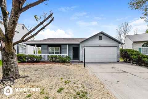 a blue house with a white garage door and a tree