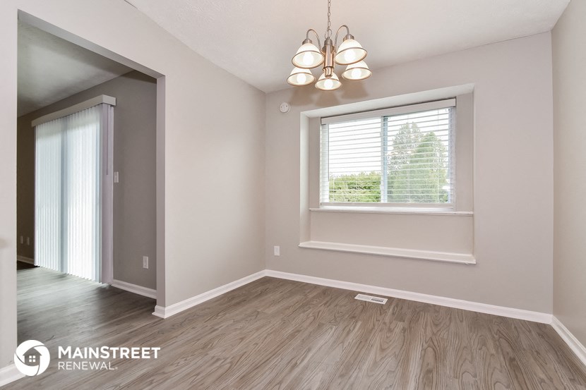 the living room of a new home with a window and wood flooring