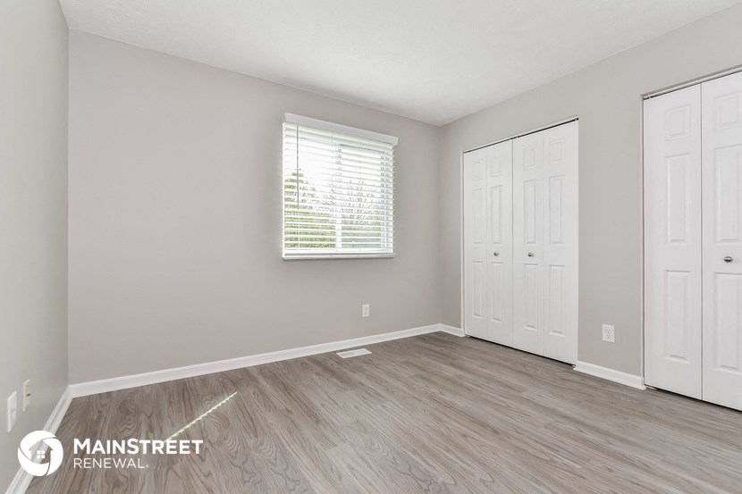 the spacious living room with two doors to the closet and a window
