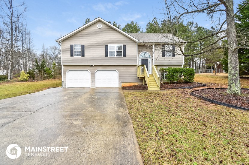 a beige house with two garage doors and a driveway