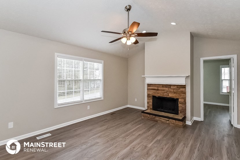 a living room with a fireplace and a ceiling fan