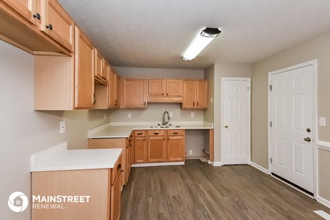 a kitchen with wooden cabinets and a white counter top and a door