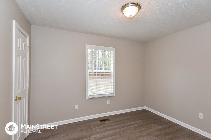 the spacious bedroom of this 2500sf home has a large window and hardwood floors
