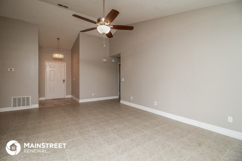 an empty living room with a ceiling fan