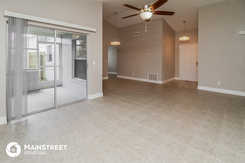 an empty living room with a ceiling fan and a sliding glass door