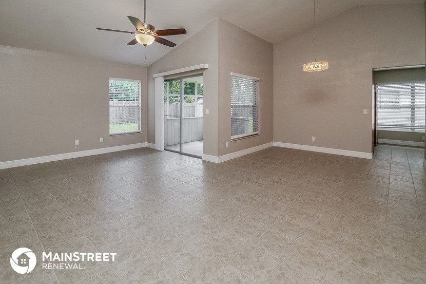 the spacious living room with tile flooring and a ceiling fan