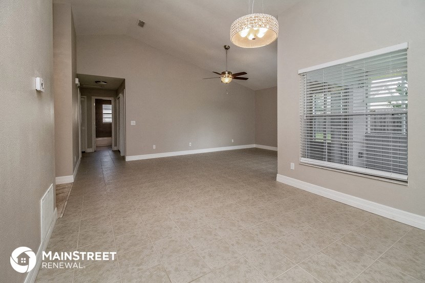 an empty living room with a ceiling fan and a large window