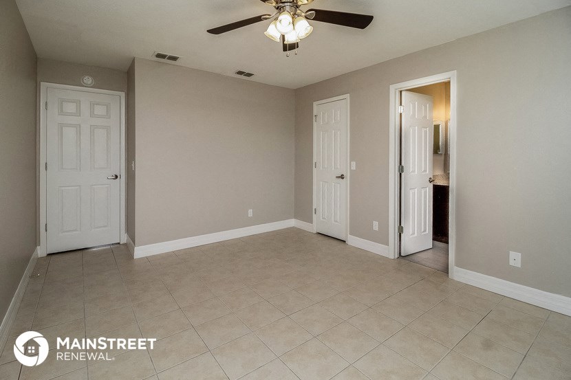 an empty living room with two doors and a ceiling fan