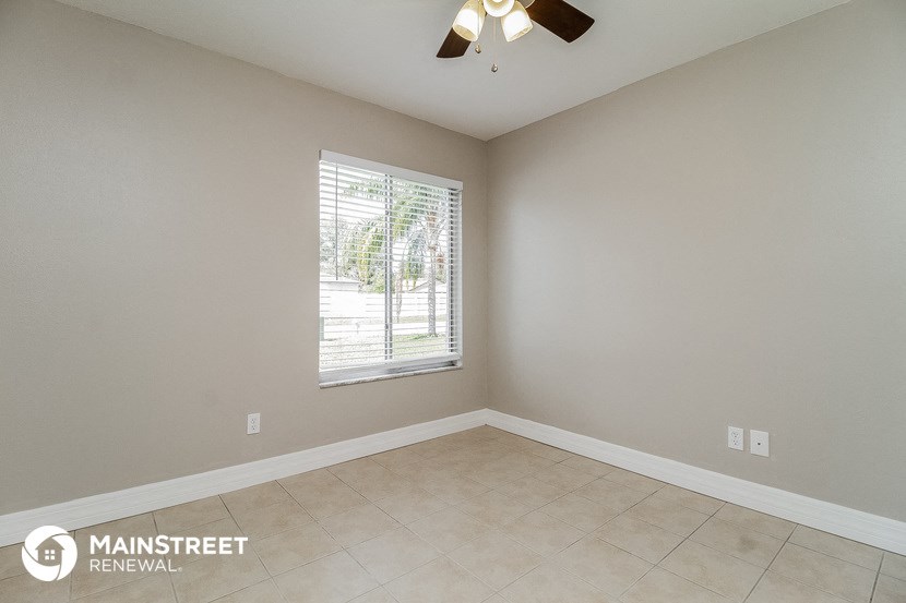 the living room of a home with a large window and a ceiling fan