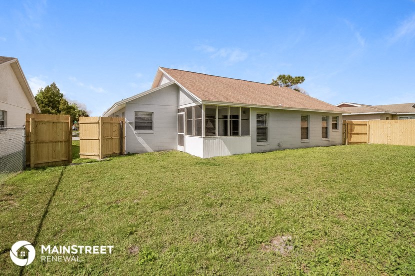 the backyard of a white house with a yard and a fence