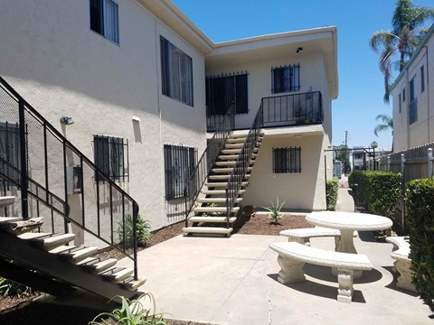 A white building with a black railing and a staircase leading to the second floor.