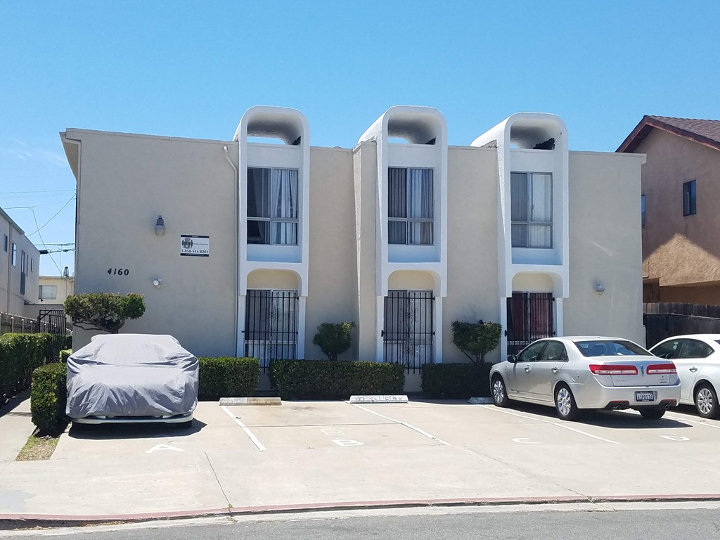A car is parked in front of a building with a sign that reads 4160.