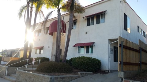A white building with a red awning and a wooden fence in front.