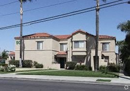 A house with a red tile roof and a palm tree in front.