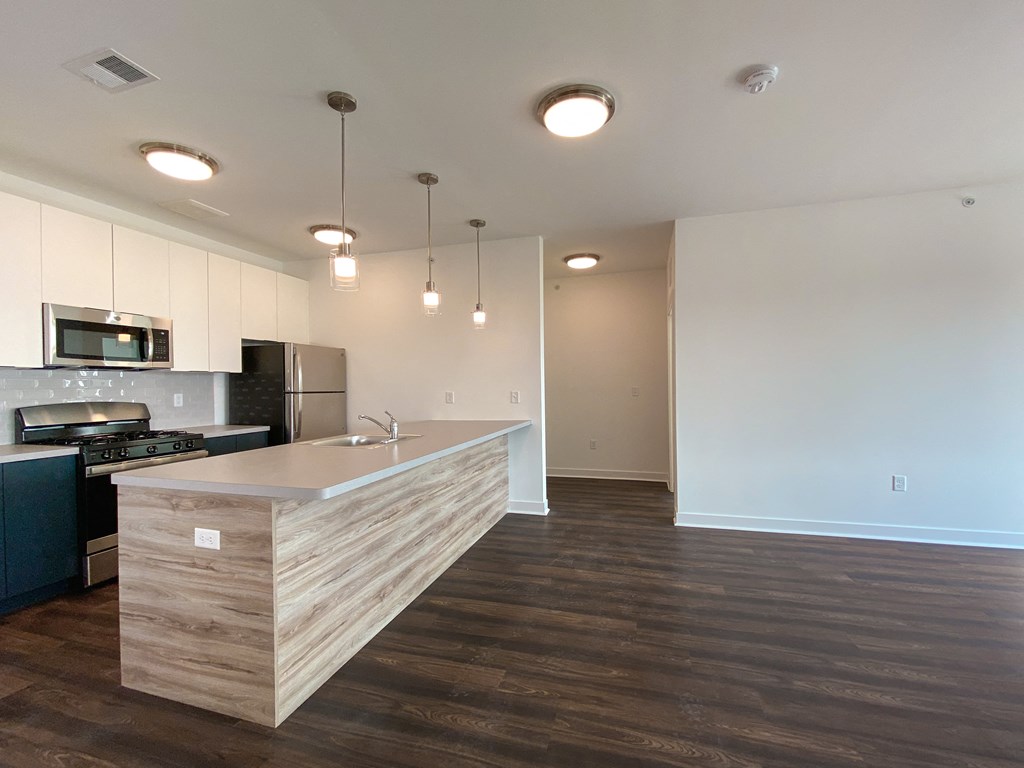 an empty kitchen with a large island and a stainless steel stove and refrigerator