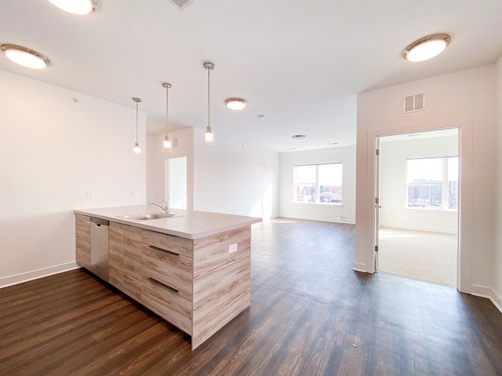 the living room and kitchen of a new home with wood floors and a large island