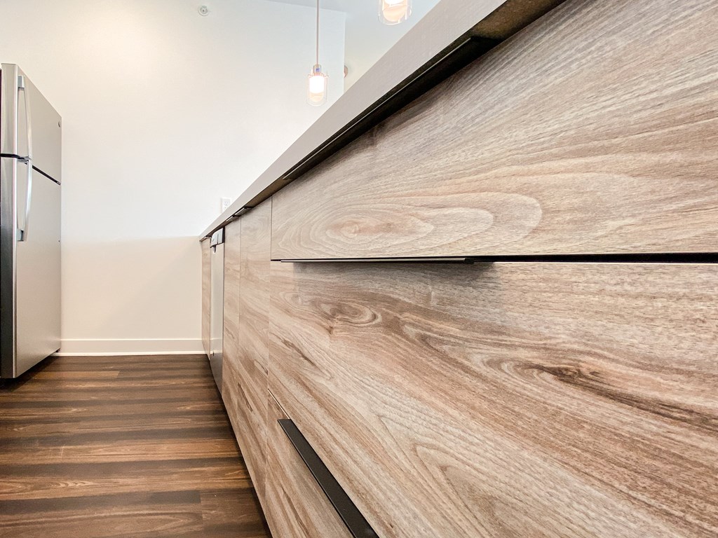 a kitchen with a wooden cabinet with a counter top and a refrigerator
