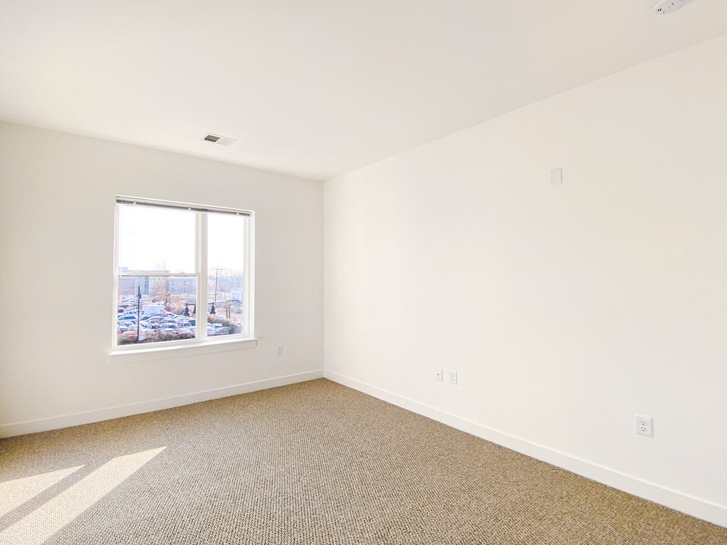 an empty room with a window and carpet