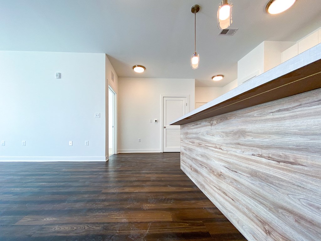 a living room with wood floors and a white wall and a staircase