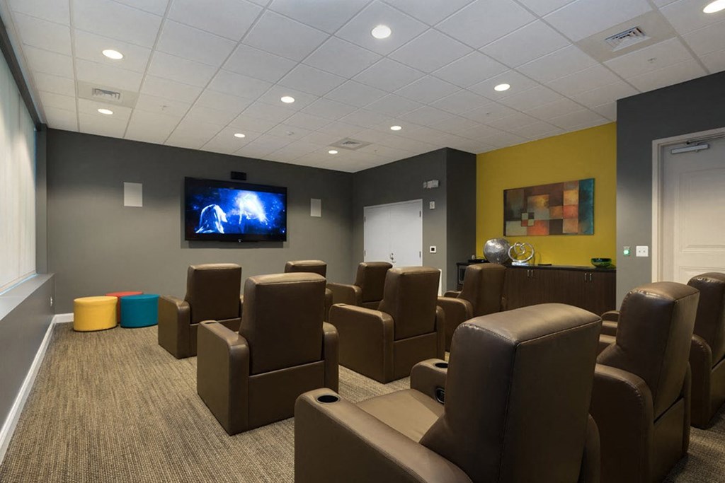 a large screening room with brown chairs and a television