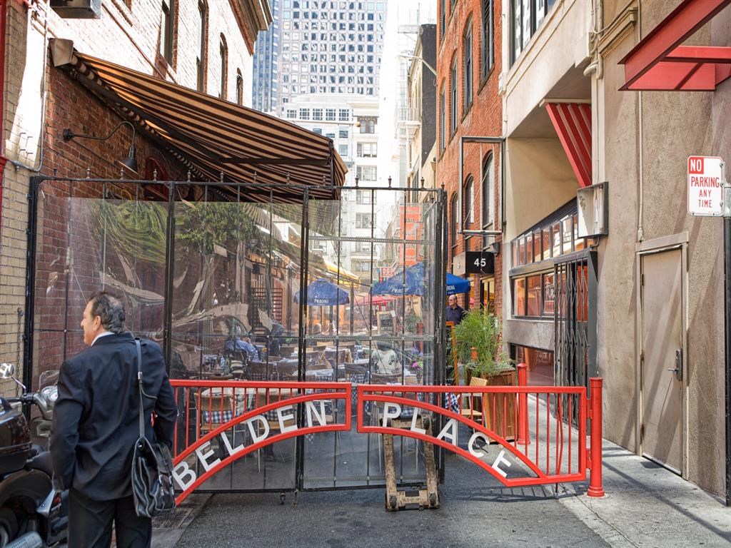 a man walking down a street next to a gate