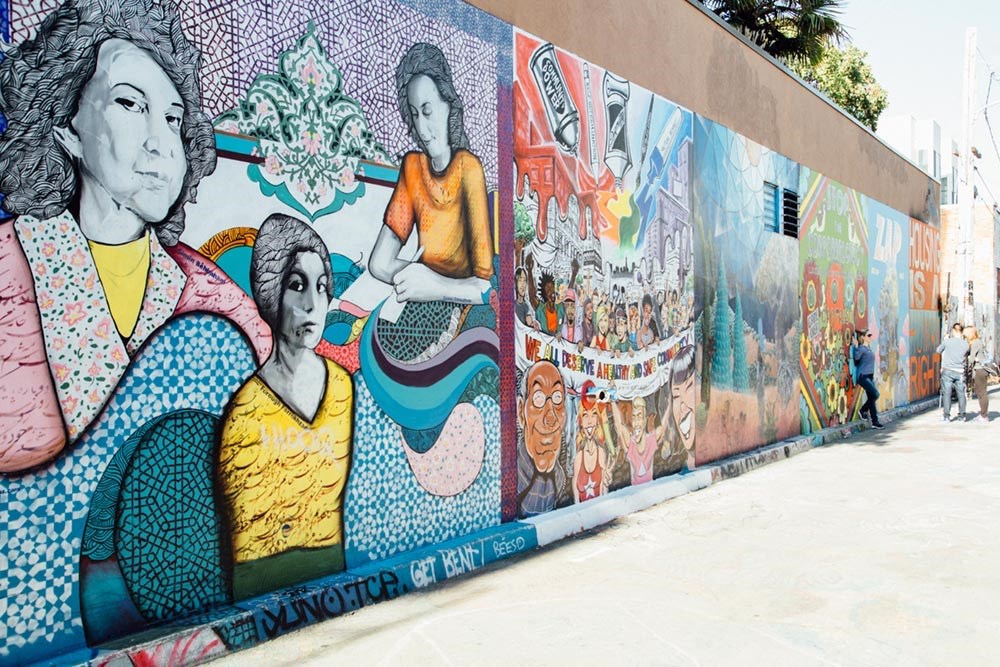 a mural on the side of a building with people walking