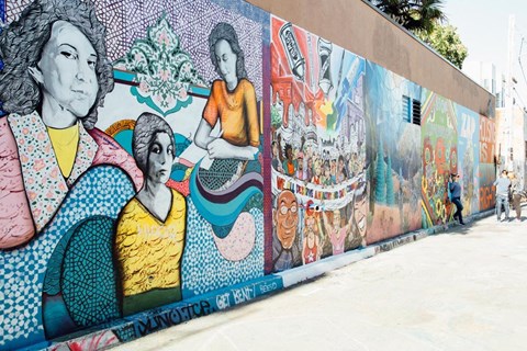a mural on the side of a building with people walking