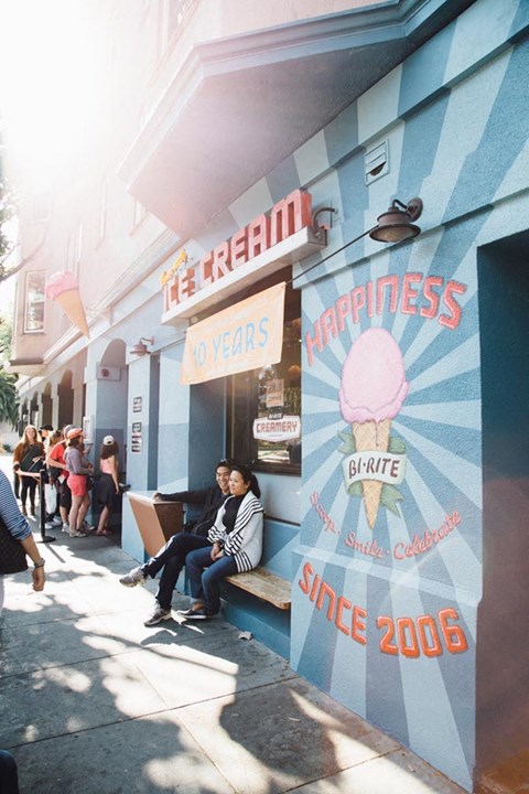 two people sitting on a bench in front of a restaurant