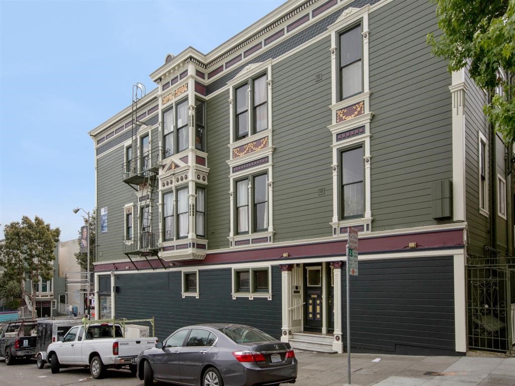 a green and gray building with cars parked in front of it
