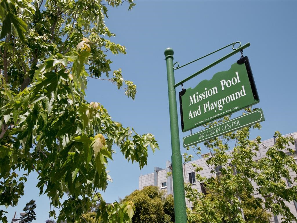 a green street sign sitting next to a tree